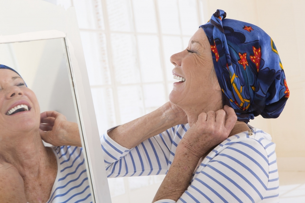 45633329 - senior woman looking at mirror and putting her scarf