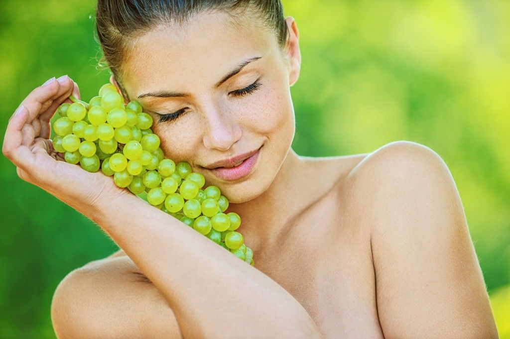 woman with bare shoulders holding grapes